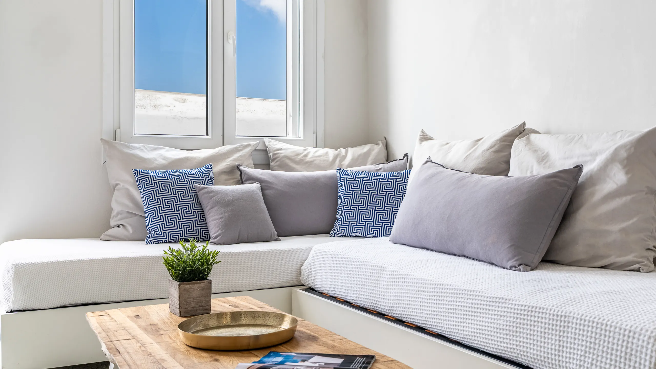 Built-in window seat with grey linen cushions and blue Greek-key patterned pillows
